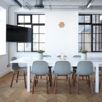Chairs surround a table with a tv in the background in a conference room.
